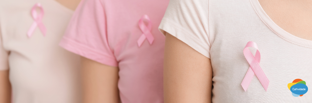 Grupo de colaboradoras vestindo rosa e segurando laços do Outubro Rosa, representando a cultura de cuidado e prevenção do câncer de mama no ambiente de trabalho.